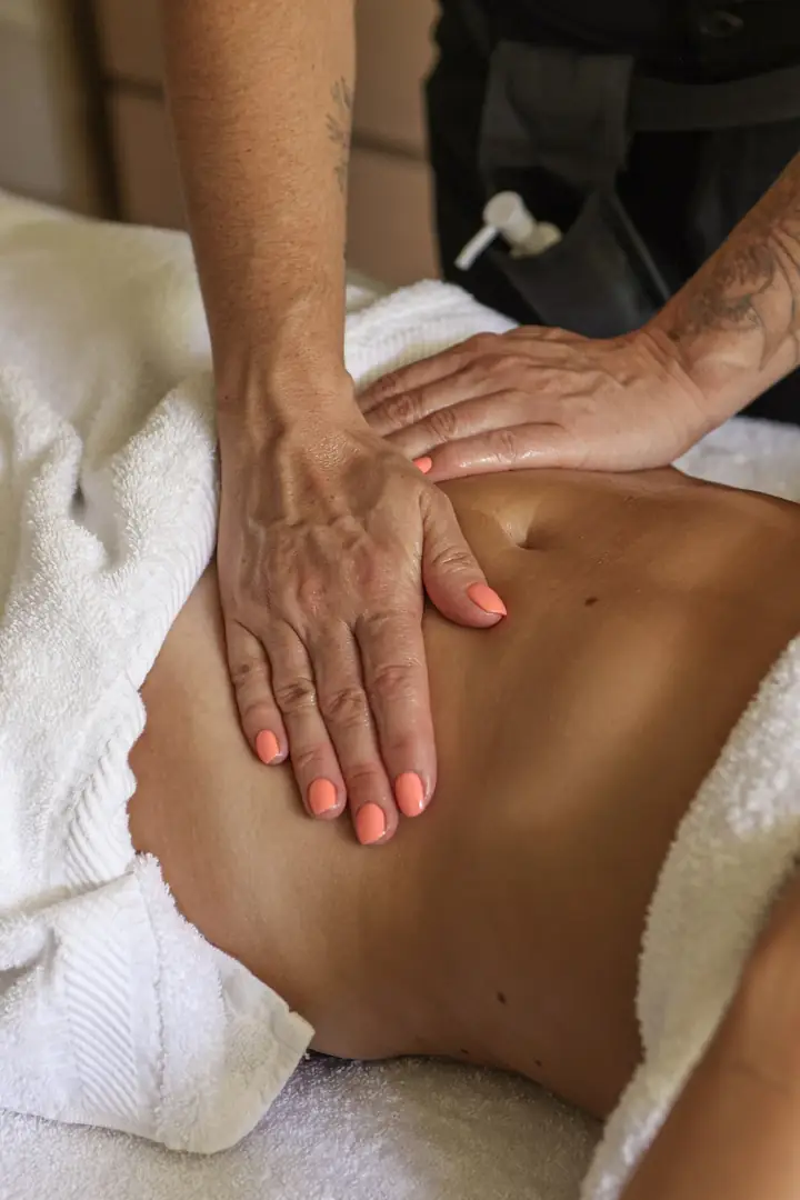 Drainage lymphatique du ventre : les deux mains de la praticienne à plat sur l’abdomen, entre deux draps blancs.